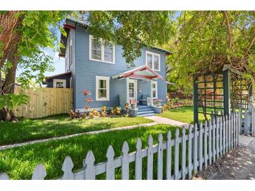 Charming blue two-story home with a well-manicured lawn, picket fence, and lush landscaping at 701 14Th N St, St Petersburg, FL 33705