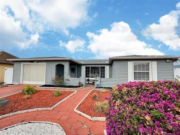 Charming single-story home with attached garage, a red brick walkway and lovely landscaping at 8413 Moulton Dr, Port Richey, FL 34668