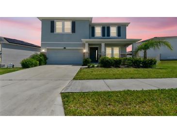 Charming two-story home featuring a manicured lawn, elegant stone accents, and an attached two-car garage at 10749 Tally Fawn Loop, San Antonio, FL 33576