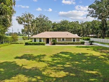 Charming single-story home featuring a well-manicured lawn and verdant shrubbery at 1414 Stephens Oak Ct, Plant City, FL 33567