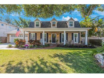 Charming brick home featuring a quaint front porch, dormer windows, and a well-manicured lawn at 2718 W Leila Ave, Tampa, FL 33611
