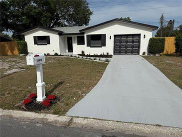 Charming single-story home featuring a freshly painted exterior, modern garage door, and a well-manicured yard at 29813 69Th N St, Clearwater, FL 33761
