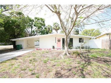 Charming single-story home boasts a pink front door, white brick, and a spacious front yard at 4735 W Wisconsin Ave, Tampa, FL 33616