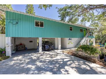 Coastal home with a vibrant turquoise exterior, ground-level garage, and staircase leading to the main entrance at 7417 Seagull Way, Tampa, FL 33635