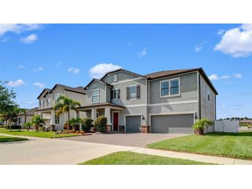 Beautiful two-story home with well-manicured lawn, brick driveway, and two-car garage at 11720 Navajo Sandstone St, Riverview, FL 33579
