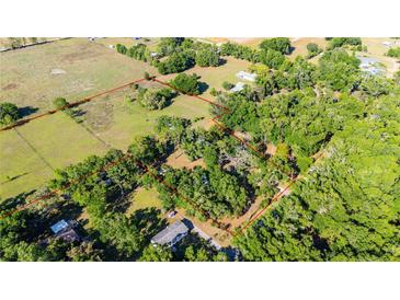 An aerial view shows the property lines and surrounding landscape with lush greenery and mature trees at 27477 Old Trilby Rd, Brooksville, FL 34602