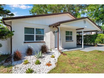 Charming home features a well-manicured lawn, complemented by decorative rock accents and lush landscaping at 2873 Karen Ave, Largo, FL 33774