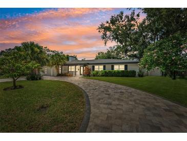 Charming single-story home featuring a lush front yard, paver driveway, and beautiful landscaping at sunset at 8231 31St N Ter, St Petersburg, FL 33710