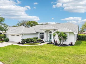 Beautiful single-story home featuring manicured landscaping, light exterior, and a well-maintained lawn at 8804 Poe Dr, Hudson, FL 34667
