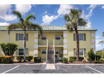 Inviting condo exterior featuring lush landscaping, palm trees, and convenient parking at 942 Capri Isles Blvd # 207, Venice, FL 34292