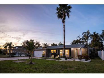 Charming single-story home featuring a well-manicured lawn, lush landscaping, and inviting front porch at dusk at 3981 Mckay Creek Dr, Largo, FL 33770