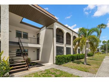 Charming condo building featuring stucco walls, arched balconies, and lush tropical landscaping at 7701 Starkey Rd # 445, Seminole, FL 33777