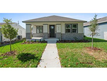 Charming single-story home showcasing a well-manicured lawn and inviting front porch with stone accents at 930 57Th N Ave, St Petersburg, FL 33703