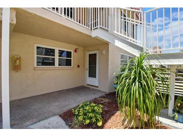 Exterior shot of condo with a white door, walkway, plants, and outdoor staircase leading to the second floor at 10035 63Rd N Ave # 12, St Petersburg, FL 33708