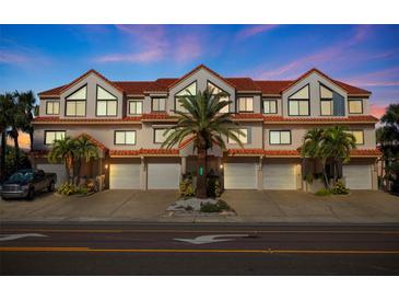 Charming townhome features multiple units, garages, tile roof, palm trees, and inviting curb appeal at 1206 Gulf Blvd # C, Indian Rocks Beach, FL 33785