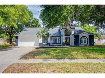 Charming single Gathering home with a beautiful lawn, mature trees, and a two car garage at 18238 Clear Lake Dr, Lutz, FL 33548