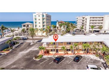 A beachfront condo building with palm trees and parking lot offers easy access to the ocean and resort amenities at 19417 Gulf Blvd # E217, Indian Shores, FL 33785