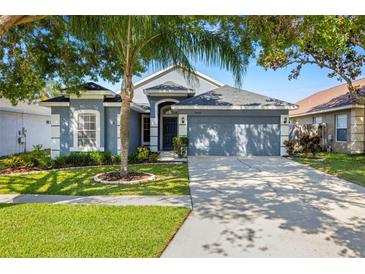 Charming single-story home featuring a well-manicured lawn, mature trees, and a two-car garage at 19505 Morden Blush Dr, Lutz, FL 33558