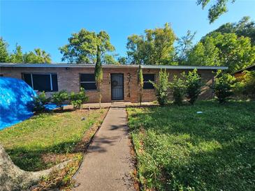 Charming brick home featuring a walkway, well-maintained landscaping and dark front door at 3714 E Ellicott St, Tampa, FL 33610