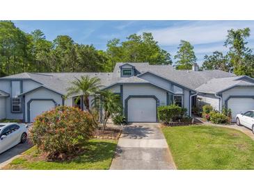 Charming single-story home with a well-manicured lawn, blossoming bushes, and attached one car garage at 39650 Us Highway 19 N # 743, Tarpon Springs, FL 34689
