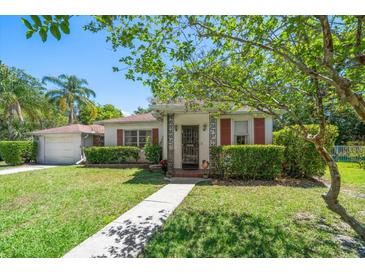 Charming single-story home with a well-manicured lawn, lush landscaping, and decorative shutters and front door at 219 Park S Cir, Dunedin, FL 34698