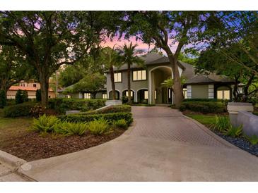 Stunning home exterior featuring a large driveway, lush landscaping, and architectural design at 6352 W Maclaurin Dr, Tampa, FL 33647