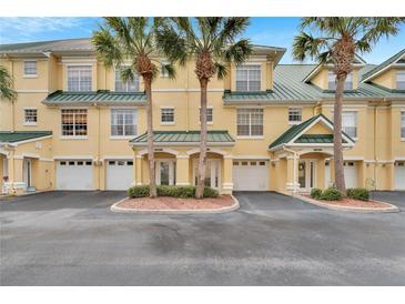 Inviting yellow townhouses feature attached garages, private entrances, and neatly trimmed landscaping with beautiful palm trees at 6414 Sunset Bay Cir, Apollo Beach, FL 33572