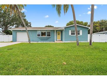 Charming blue single-story home with a green lawn and inviting yellow door at 7690 91St St, Seminole, FL 33777