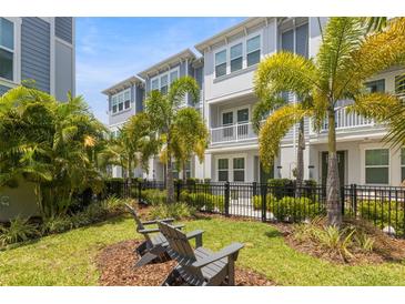 Beautiful townhome with lush landscaping, a small yard, and relaxing gray Adirondack chairs on mulched bed at 206 S Tampania Ave # 4, Tampa, FL 33609