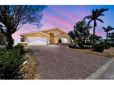 Beautifully landscaped home featuring a brick driveway and lush tropical greenery at 17 Bellevue Dr, Treasure Island, FL 33706