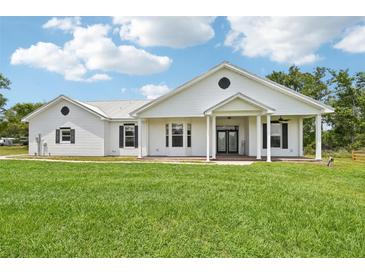 Charming one-story home featuring a metal roof, covered porch, green grass and black shutters at 21019 Lonesome Acre Rd, Wimauma, FL 33598