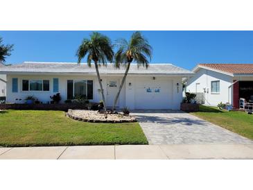 Charming single-story home with a well-maintained lawn, palm trees and brick-paved driveway at 3436 100Th N Ave, Pinellas Park, FL 33782