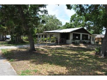 Charming single-story home with a covered front porch and mature trees surrounding the property at 601 W College Ave, Ruskin, FL 33570