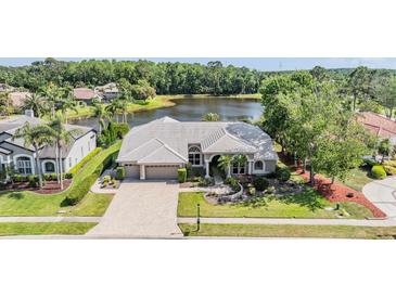 A charming home with a tile roof is situated on a lush, green lot near a tranquil lake, offering beautiful curb appeal at 1307 Forestedge Blvd, Oldsmar, FL 34677