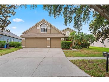 Charming two-story home featuring a three-car garage, manicured lawn, and mature landscaping at 16119 Bridgedale Dr, Lithia, FL 33547