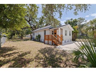 Landscaped yard surrounds this cozy home with a charming wooden porch, perfect for enjoying outdoor living at 3230 Queensboro S Ave, St Petersburg, FL 33712