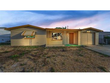 Charming single-story home featuring a light-colored exterior, attached garage, and front yard at 4920 Zodiac Ave, Holiday, FL 34690