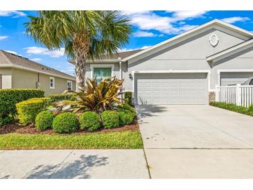 Charming single-Gathering home featuring a well-manicured lawn, mature landscaping, and a two-car garage at 7405 Stonebrook Cir, Wesley Chapel, FL 33545