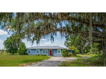Charming single-story home features a metal roof, mature trees, and a well-manicured lawn at 11015 S County Road 39, Lithia, FL 33547