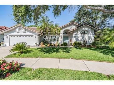 Charming single-story home featuring a well-manicured lawn, mature landscaping, and a two-car garage at 1119 Hounds Run, Safety Harbor, FL 34695