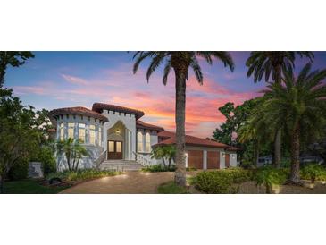 Elegant two-story home with a red tile roof, lush landscaping, and a brick driveway at sunset at 2613 N Dundee St, Tampa, FL 33629
