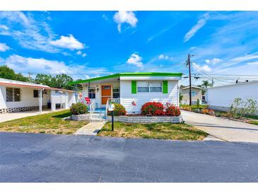 Charming single-story home with vibrant green trim and colorful flower bushes at 27466 Us Highway 19 N # 56, Clearwater, FL 33761