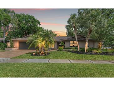 Charming single-story home with mature landscaping, brick driveway, and inviting curb appeal at sunset at 3320 Pattie Pl, Palm Harbor, FL 34685