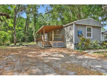 Inviting single-story home with covered porch and lush greenery creates a serene and private outdoor atmosphere at 9132 Mango St, New Port Richey, FL 34654