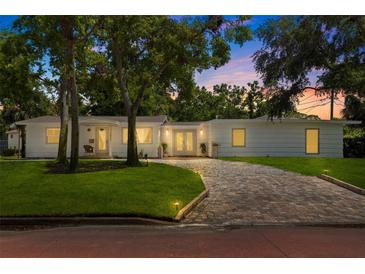Charming single-story home with mature landscaping and a brick driveway at dusk at 1800 Mound S Pl, St Petersburg, FL 33712