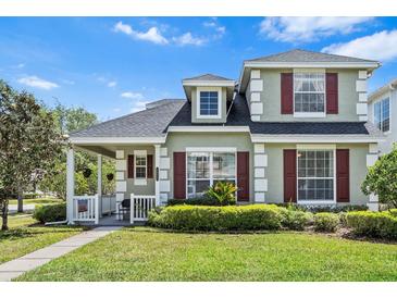 Charming two-story home with lush landscaping, covered porch, and red window shutters at 20053 Heritage Point Dr, Tampa, FL 33647