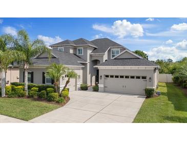 Beautiful two-story home featuring a three-car garage, well-manicured lawn, and lush tropical landscaping at 3142 Stonegate Falls Dr, Land O Lakes, FL 34638