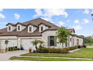 Beautiful home exterior featuring stone accents, a well-manicured lawn, and a three-car garage at 4354 Barletta Ct, Wesley Chapel, FL 33543