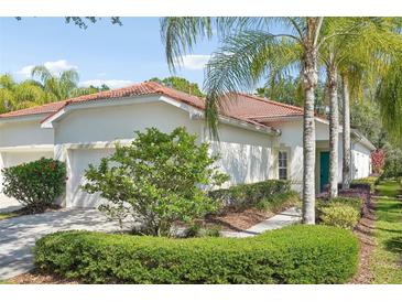Charming home features a red tile roof, lush landscaping, and a quaint, inviting entrance at 10260 Devonshire Lake Dr, Tampa, FL 33647