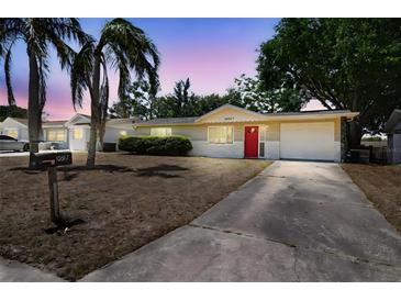 Charming single-story home featuring a red front door and well-maintained landscaping at 10817 Kingsbridge Rd, Port Richey, FL 34668